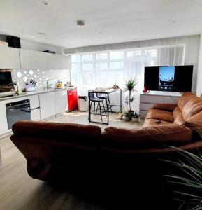 a living room with a brown couch and a kitchen at Luxury 1 bed apartment-sea view in Bournemouth