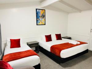 a bedroom with two beds with red and white sheets at 18th Avenue Thermal Motel in Tauranga