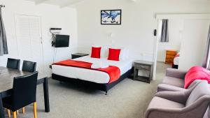 a bedroom with a bed and a table and a couch at 18th Avenue Thermal Motel in Tauranga