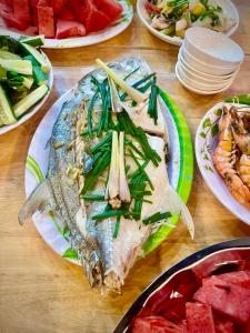 a table topped with plates of food with fish and watermelon at THUẬN VƯƠNG Homestay in Vĩnh Hy