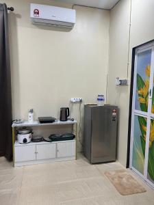 a kitchen with a stove and a refrigerator in a room at Safiyya Homestay in Kota Bharu