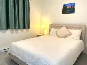 a bedroom with a white bed with a green curtain at Summer Breeze in Sooke