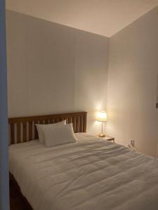 済州市にあるBibidoongdoongのベッドルーム(ランプ付きの白い大型ベッド1台付)