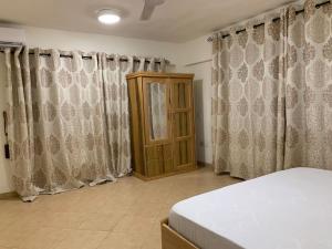 1 dormitorio con cortinas, 1 cama y armario en Cozy One Bedroom Apartment near KNUST & CCC, en Kumasi