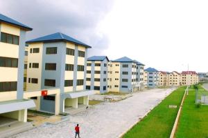 a man standing in front of a row of apartment buildings at Cozy One Bedroom Apartment near KNUST & CCC in Kumasi