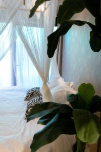 a bedroom with a white bed with a window at Bali Serenity Balnéo et lit rond in Lagnieu