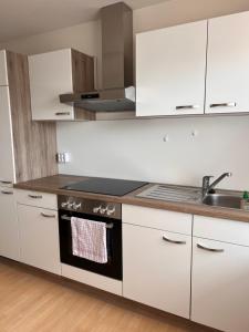 uma cozinha com armários brancos e um forno com placa de fogão em Gäste, Handwerker Zimmer - 2 Betten em Rosenfeld
