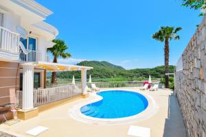 a villa with a swimming pool and palm trees at Villa Tia in Ortaca