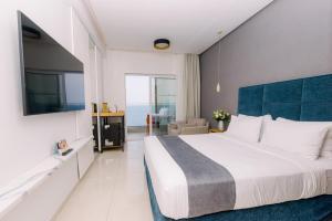 a bedroom with a large bed with a blue headboard at Ray Hotel Corfu in Perama