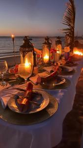 een tafel met borden eten en kaarsen op het strand bij Três Sereias - 3 Mermaids in Govuro