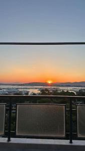 a bench on a balcony with the sunset in the background at Floisvos Penthouse Oasis in Athens