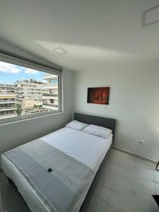 a bed in a room with a large window at Floisvos Penthouse Oasis in Athens