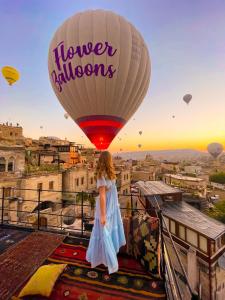 a girl standing on a balcony looking at a hot air balloon at Angel View Suites in Goreme