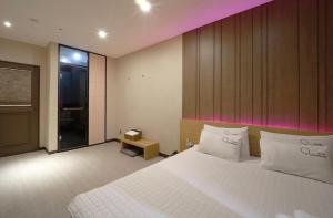 a bedroom with a large white bed and a window at Nampo Comma Hotel in Busan