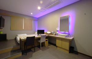 um quarto com uma secretária, uma cama e um espelho. em Nampo Comma Hotel em Busan