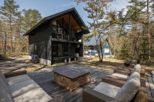a house with a wooden deck with a table at Muskoka House — Stunning architect-designed chalet in Hakuba