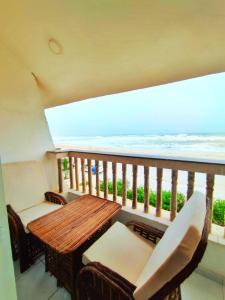 a balcony with a wooden table and chairs and the ocean at SEA VILLAS Salalah in Salalah