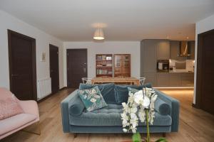 ein Wohnzimmer mit einem blauen Sofa und einer Küche in der Unterkunft Seaview Point, Superb 2- bedroom flat, 12th Floor in Southend-on-Sea