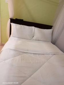 łóżko z białą pościelą i poduszkami w pokoju w obiekcie Wusiiza Homestay Kisumu w mieście Kisumu