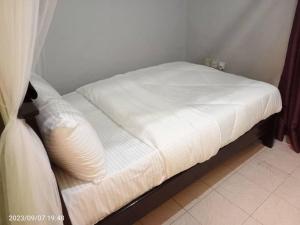 Una cama con sábanas blancas y una almohada. en Wusiiza Homestay Kisumu, en Kisumu