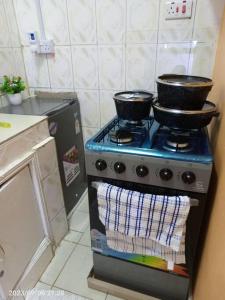 una cocina con fogones con ollas y sartenes. en Wusiiza Homestay Kisumu, en Kisumu