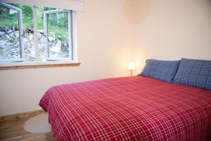 um quarto com uma cama com um cobertor vermelho e 2 janelas em Lochleven Seafood Cottage em Onich
