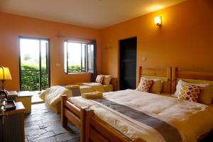 Depche Village Resort في حديقة بانديبور الوطنية: سريرين في غرفة بجدران برتقالية ونوافذ