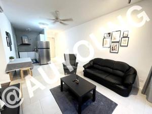 a living room with a black leather couch and a refrigerator at Geo Bukit Rimau Apartment in Shah Alam