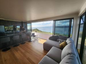 a living room with a couch and a view of the ocean at Ocean Waters in Mahia