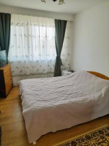 Schlafzimmer mit einem großen weißen Bett und Vorhängen in der Unterkunft Apartment Eminescu - A pleasant stay in Bacau in Bacău
