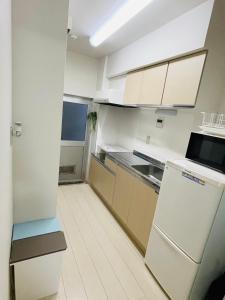 a kitchen with white cabinets and a refrigerator at STUDIO YONEGAHAMA l 米が浜通 in Yokosuka