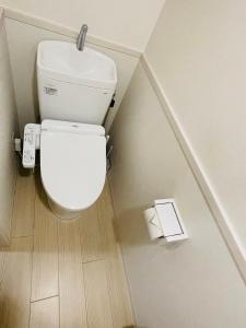 a white toilet in a bathroom with a roll of toilet paper at STUDIO YONEGAHAMA l 米が浜通 in Yokosuka