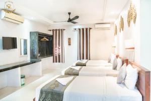 a hotel room with three beds and a tv at Saline Residence in Siem Reap