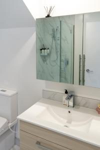 een witte badkamer met een wastafel en een spiegel bij The happy hideaway 2 bed 2 bath in Christchurch