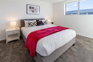 een slaapkamer met een groot bed met een rode deken erop bij The happy hideaway 2 bed 2 bath in Christchurch