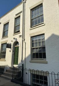 a white brick building with a green door at The Spring Bank APARTHOTEL in Preston