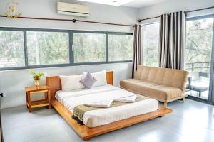 a bedroom with a bed and a couch and windows at Saline Residence in Siem Reap +30 photos