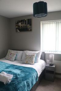 a bedroom with a bed with a blue blanket and a window at Coleridge house Private parking NETFLIX in Swindon