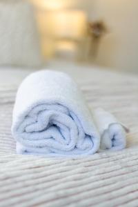 een rol witte handdoek op een bed bij The happy hideaway 2 bed 2 bath in Christchurch