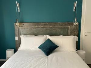 a bed with white pillows and a blue wall at Ca'Sazen Trilo 19 in Brescia