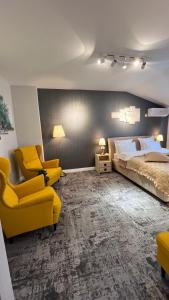 a bedroom with a bed and two yellow chairs at Complex Rediu 54 Luxury Apartaments in Iaşi