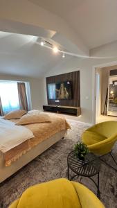 um quarto com uma cama, uma televisão e uma cadeira em Complex Rediu 54 Luxury Apartaments em Iaşi