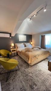 ein großes Schlafzimmer mit einem großen Bett und einem gelben Stuhl in der Unterkunft Complex Rediu 54 Luxury Apartaments in Iaşi