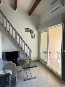un salon avec un escalier et une table en verre dans l'établissement JEAN BART III Joli T2 cabine mezzanine proche plage Richelieu Cap d'Agde, au Cap d'Agde