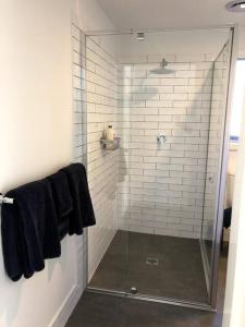ein Badezimmer mit einer Glasdusche und schwarzen Handtüchern in der Unterkunft Adorable 1 bedroom guesthouse with firepit in Primbee