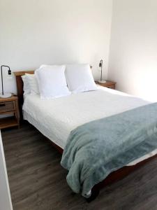 Schlafzimmer mit einem Bett mit weißer Bettwäsche und Kissen in der Unterkunft Adorable 1 bedroom guesthouse with firepit in Primbee