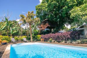 una piscina con una casa sull'albero sullo sfondo di Tree Lodge Mauritius Villa a Argy