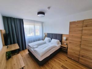 a bedroom with a bed and a large window at Mountains & Lakes - Chaletdorf in Villach