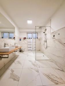 a white bathroom with two sinks and a shower at Mountains & Lakes - Chaletdorf in Villach