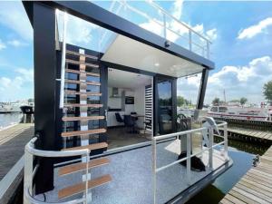 ein Haus am Wasser mit einem Dock in der Unterkunft Tiny Houseboat Luxery in Zeewolde